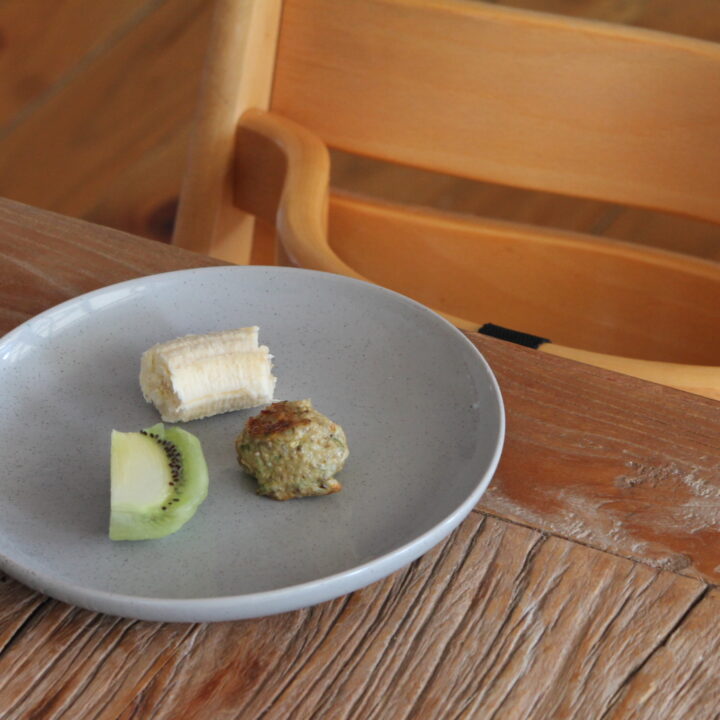 plate on table with chicken meatball banana and kiwifruit in front of high chair