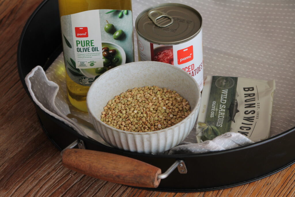 Ingredients in baby food buckwheat puttanesca on a black tray with white cloth underneath