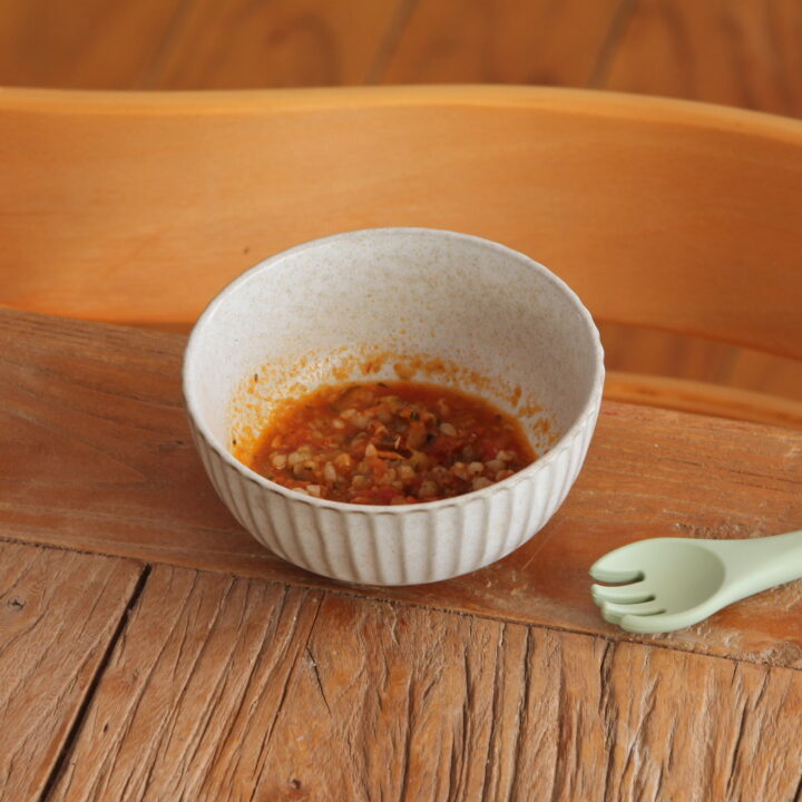 bowl containing baby food buckwheat puttane sca on a table in front of highchair with baby spoon