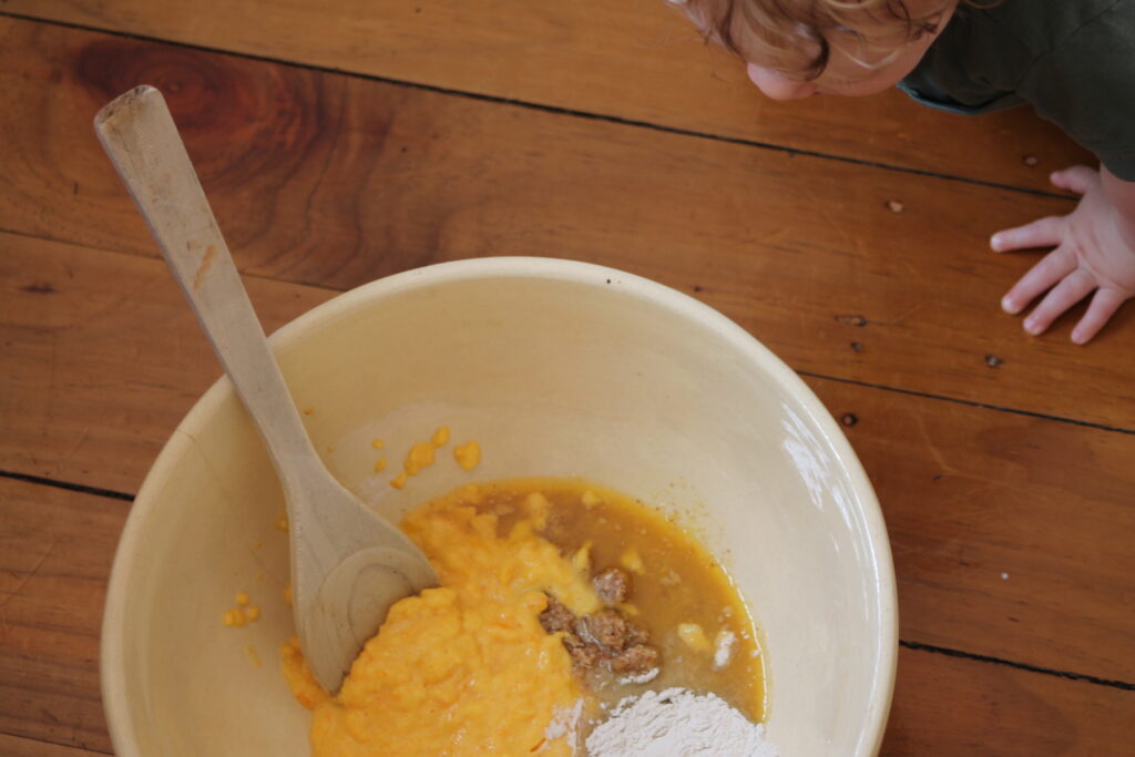 Bowl with raw ingredients to make cake batter baby peeping in