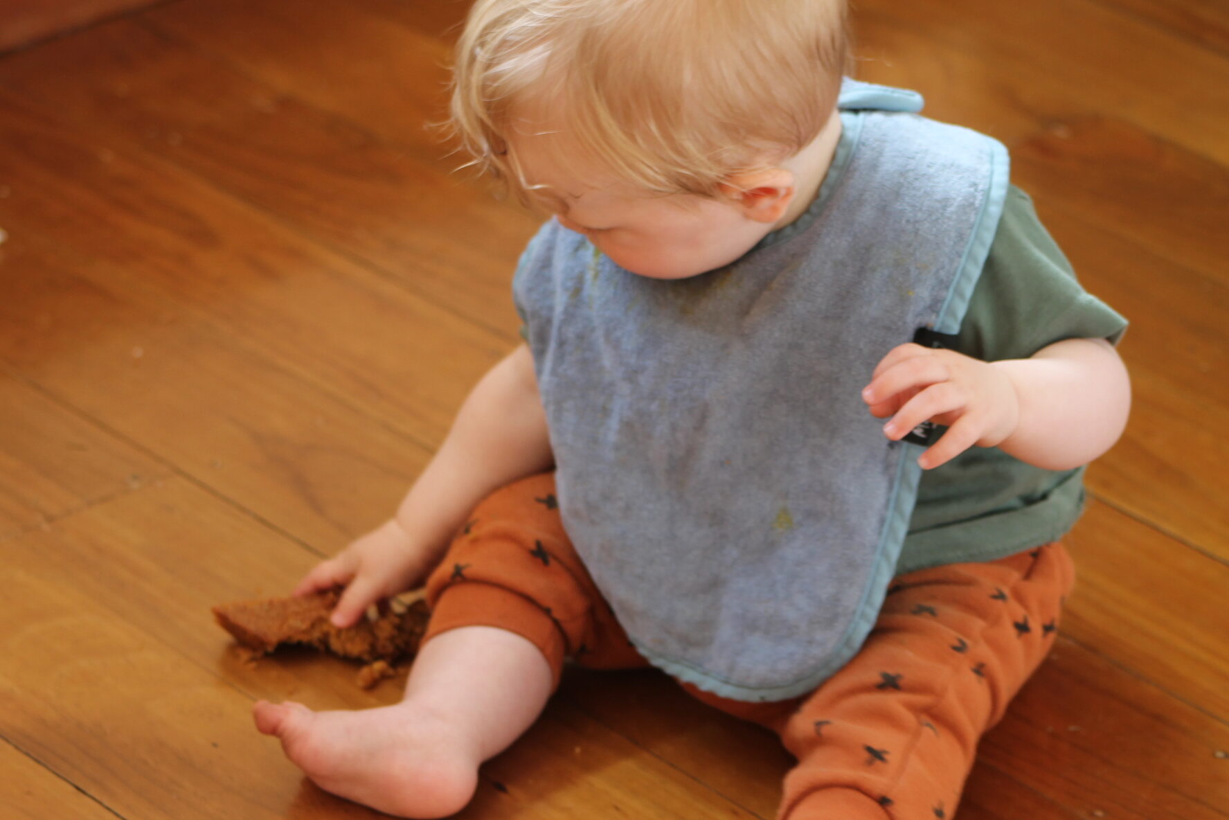baby on floor eating whole orange cake