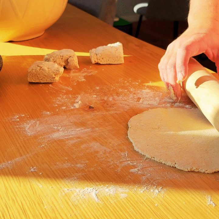 rolling oatmeal flatbread dough out on wooden table