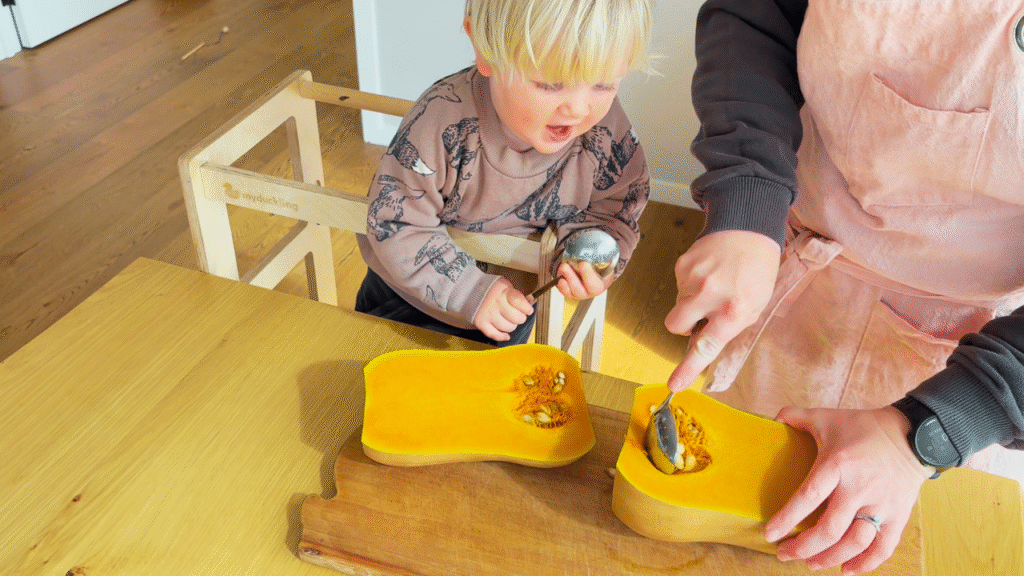 Toddler helping to scoop seeds from pumpkin for pumpkin and sage cob loaf
