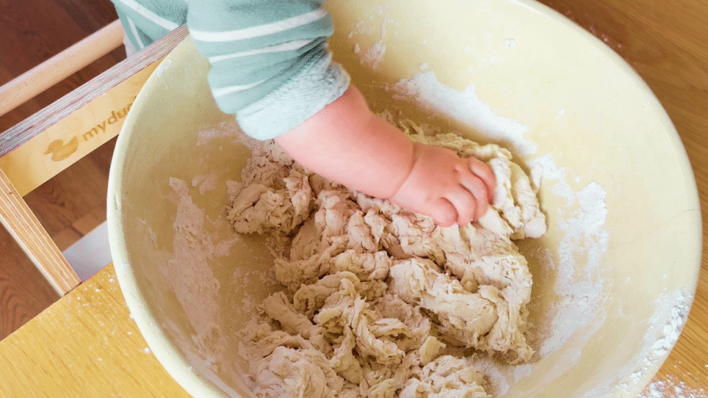 Toddler hand helping to mix dough for tiger loaf