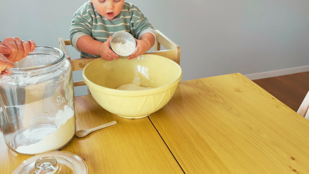 Toddler adding flour to make dough for tiger loaf