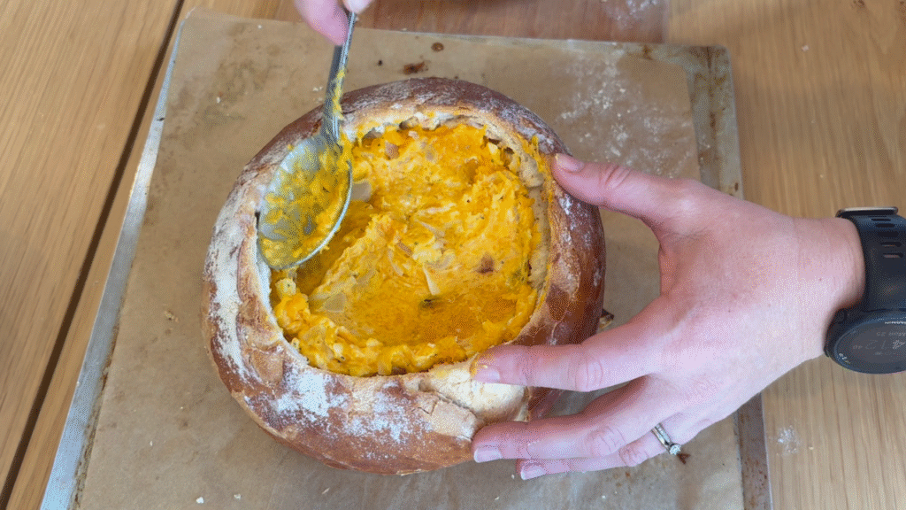 Spooning mixture into a pumpkin and sage cob loaf
