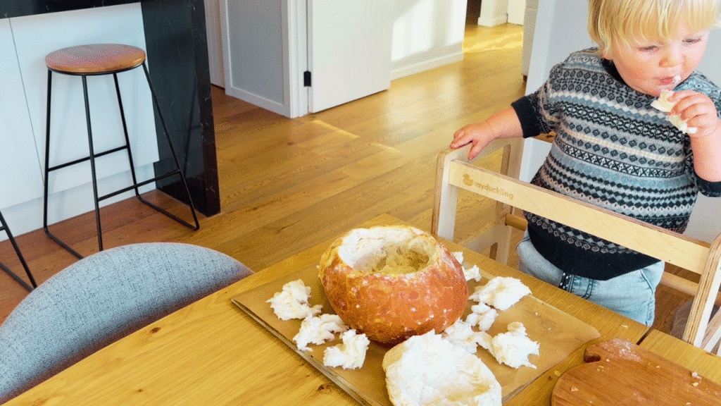 Toddler eating bread while cob loaf is prepared