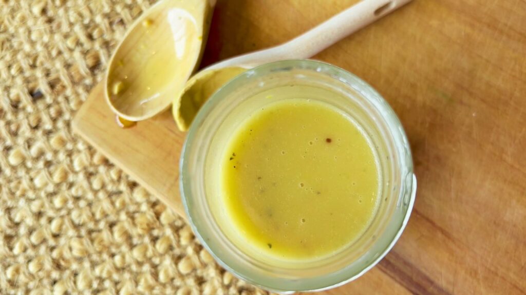 Honey mustard dressing in jar on wooden board