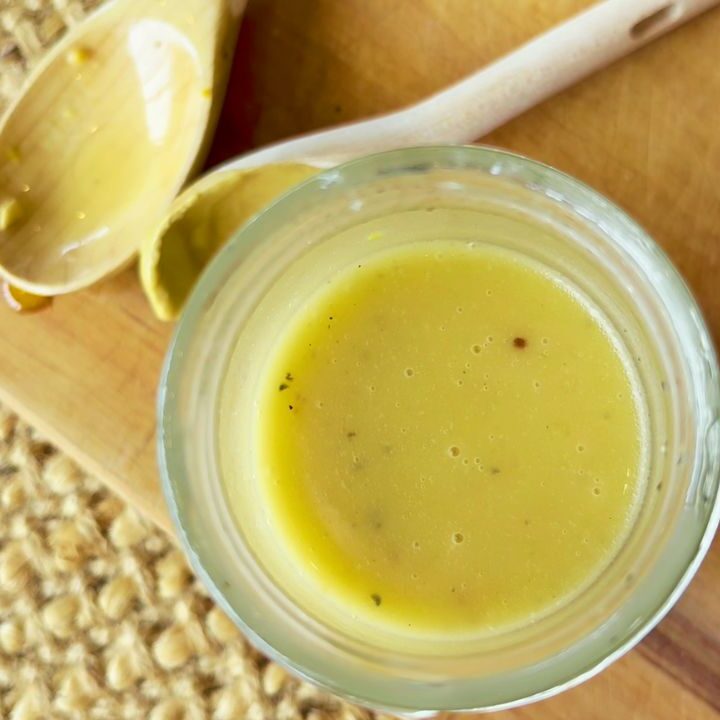 Honey mustard dressing in jar on wooden board