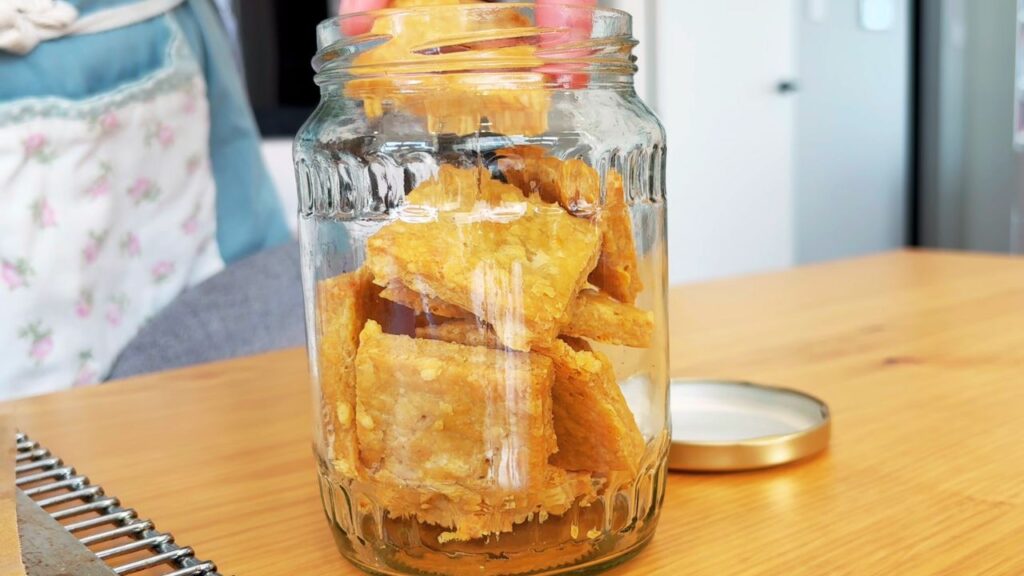 Toddler friendly winter cheese cracker snacks being placed in a glass jar