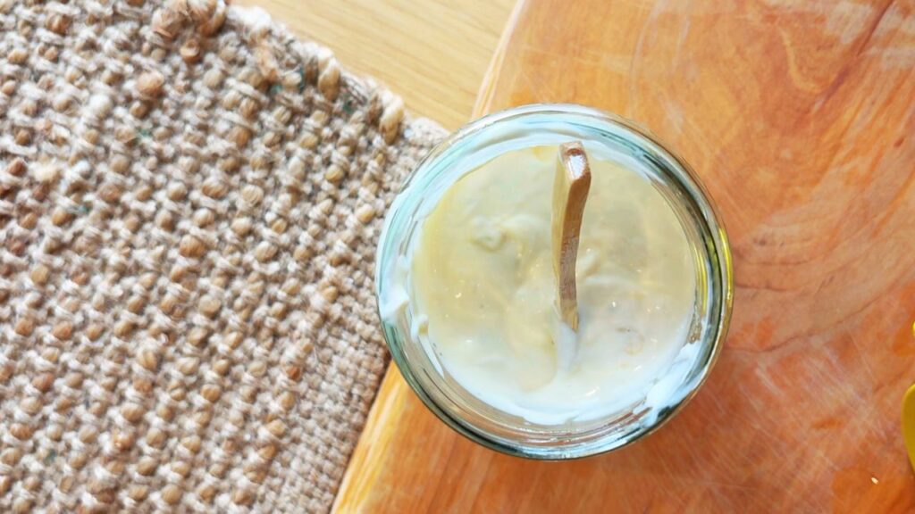 Homemade seed oil free mayo with wooden spoon in jar