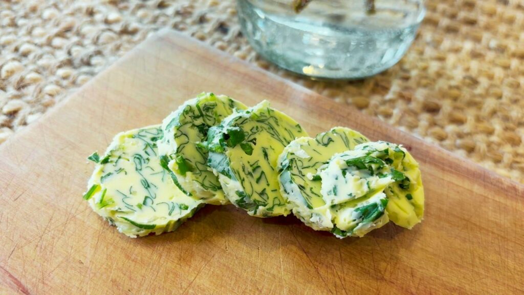 from scratch garlic and herb butter sliced on a wooden board at the table
