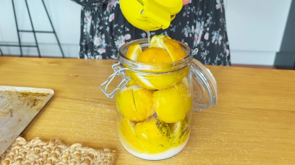 lemon juice being added to salt preserved lemon jar