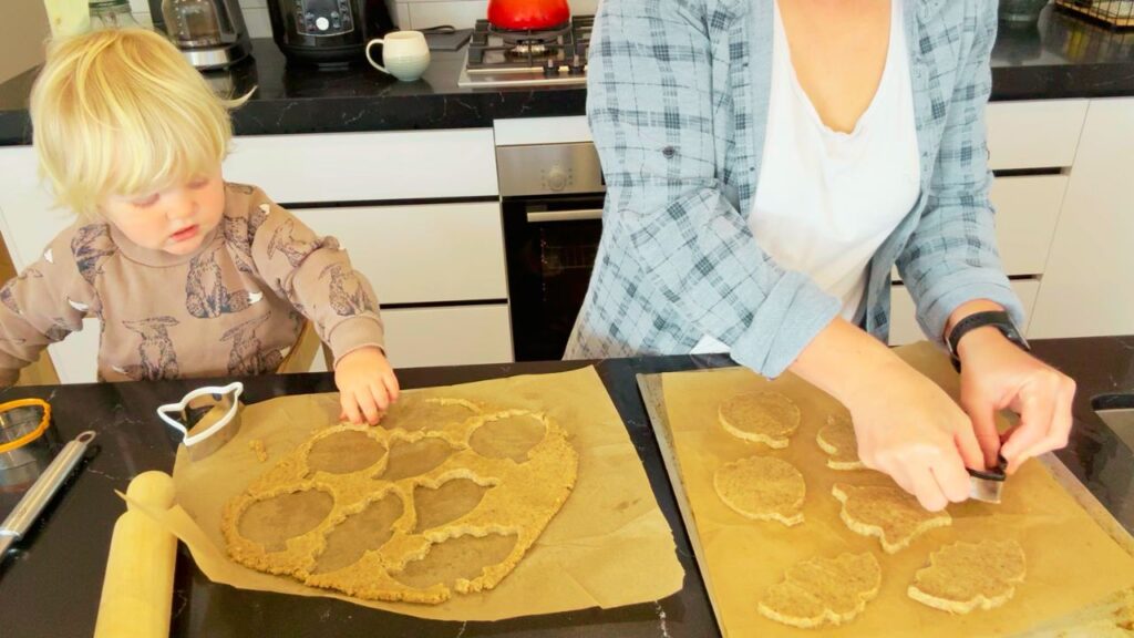 Toddler helping make refined sugar free Halloween cookies with mom in the kitchen.