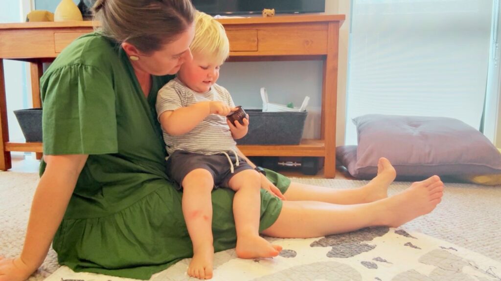 Mother and toddler sitting together, applying homemade plantain salve to a bite or scrape — natural itch relief at home.