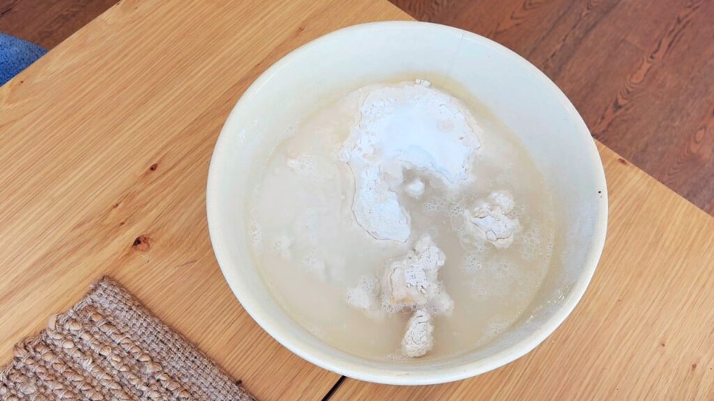 Adding flour and starter to a mixing bowl while making healthy seed-oil-free sourdough bread at home.