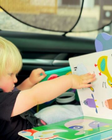 Toddler looking through books while traveling in the car