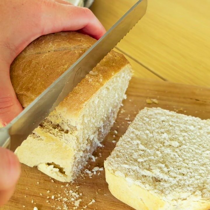 Cutting into a freshly baked sourdough sandwich loaf made without seed oils or vegetable oil.
