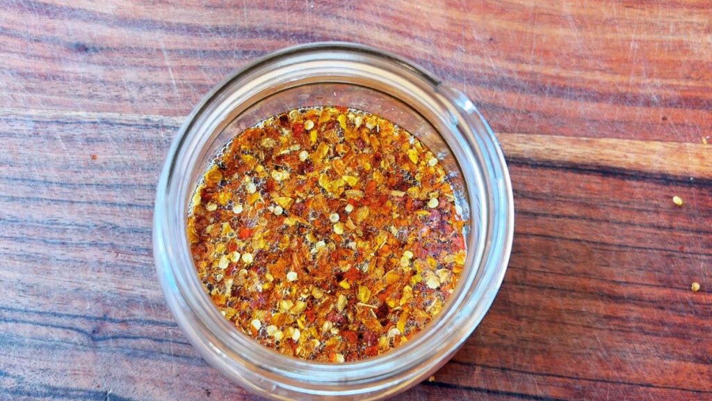 Close-up of homemade chili oil with chili flakes and golden avocado oil, a gut-healthy seed-oil-free condiment.