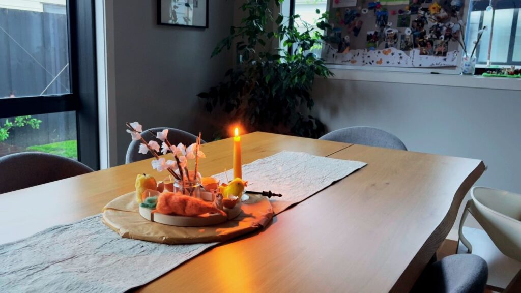 Waldorf-inspired dining table centerpiece with a lit beeswax candle creating a warm, seasonal atmosphere