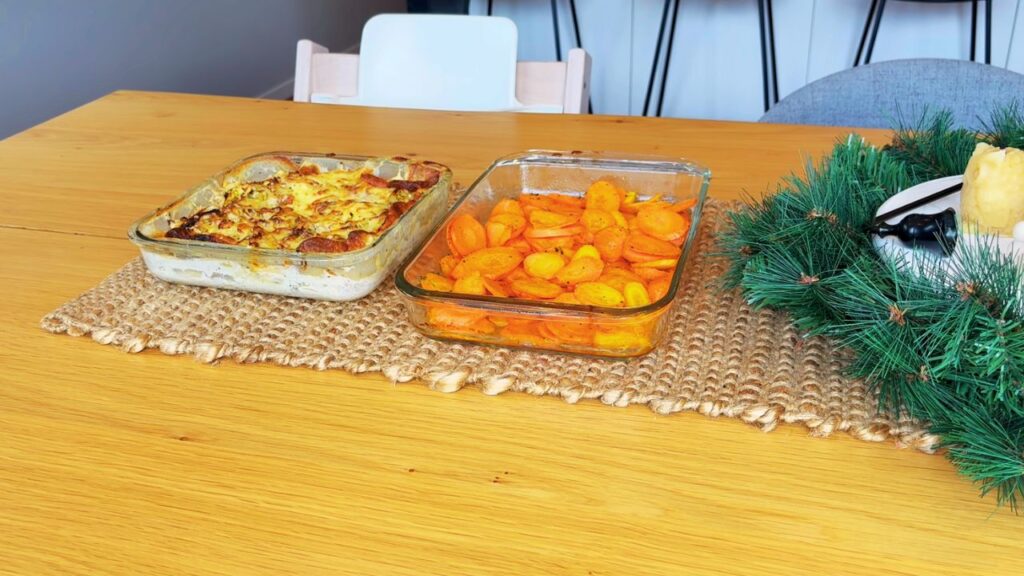 Honey–roasted carrots and potato leek gratin cooling on the kitchen table as part of simple holiday side dishes.