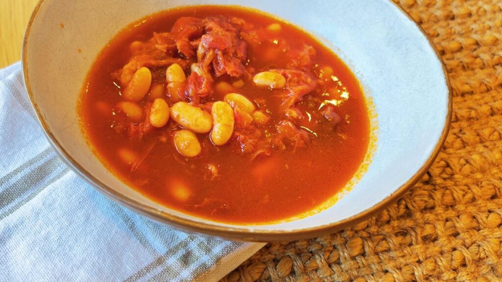 Bowl of ham hock baked beans in tomato sauce served as a nourishing, protein-rich breakfast