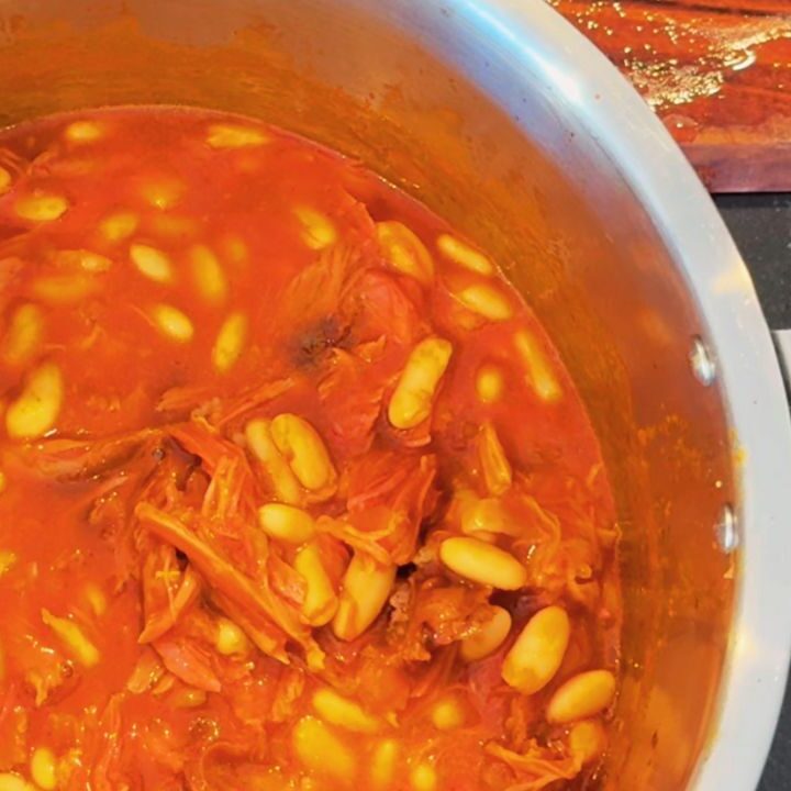 Ham hock baked beans simmering in a rich tomato sauce, made from scratch as a gut-friendly, high-protein breakfast option.