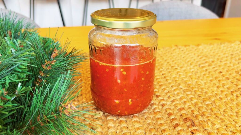 Homemade chili jam in a glass jar, a festive make-ahead condiment to serve alongside simple holiday side dishes.