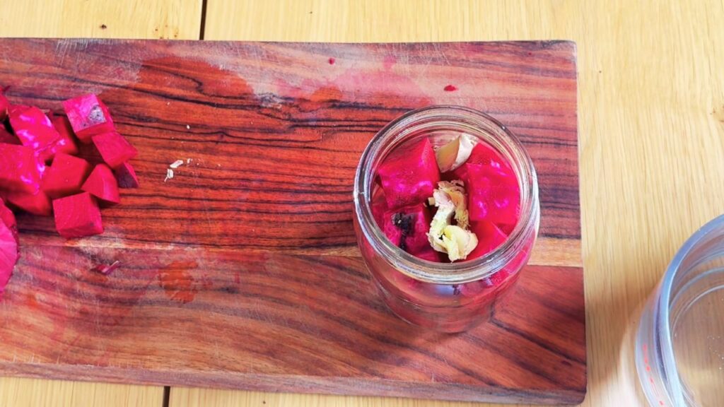 Glass jar filled with beetroot and ginger before adding brine for beetroot kvass