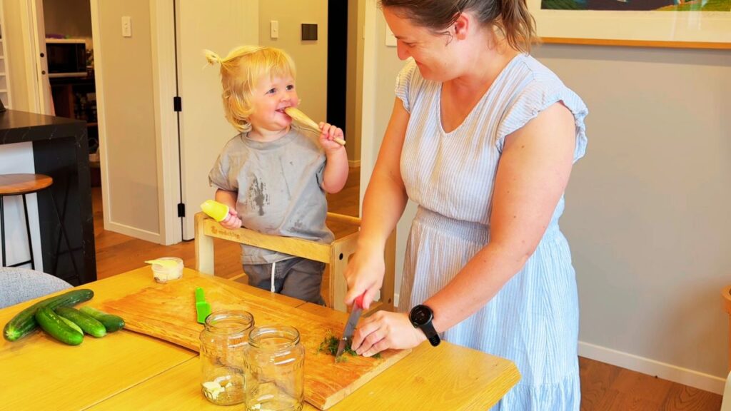 toddler helping in the kitchen while mother prepares food calmly