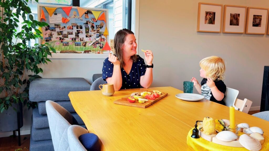 Mother and toddler sharing a relaxed meal together at the table, enjoying a slow moment at home.