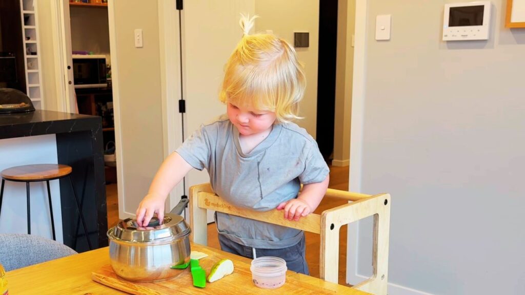toddler concentrating at the kitchen bench during everyday family life