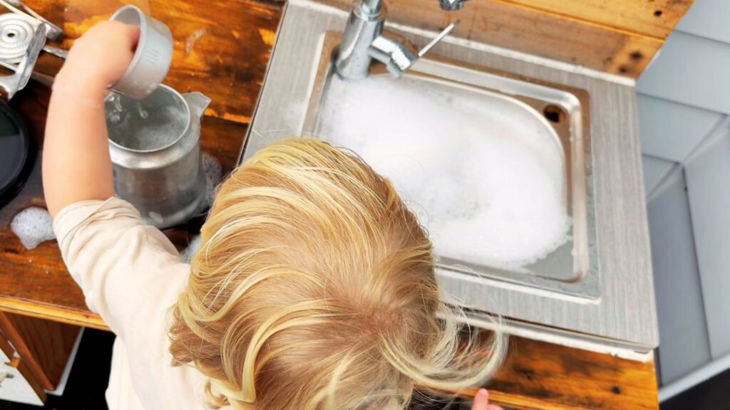 toddler playing with water at the sink during calm everyday family life