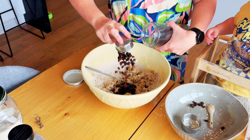 Adding raisins to oat cookie dough for natural sweetness in toddler cookies